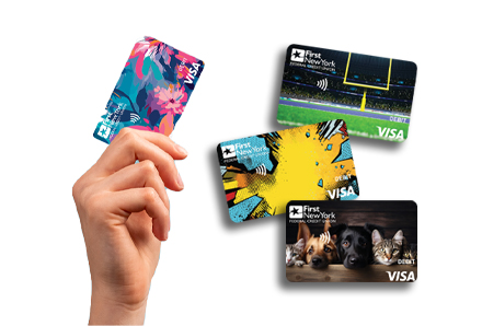 hand holding up a floral visa card and three additional visa cards to the right